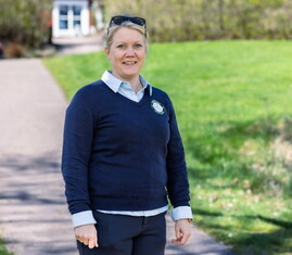 Bild på Lena Björkdahl som är klubbchef för Köpings Golfklubb. Hon står utomhus utanför golfklubben.