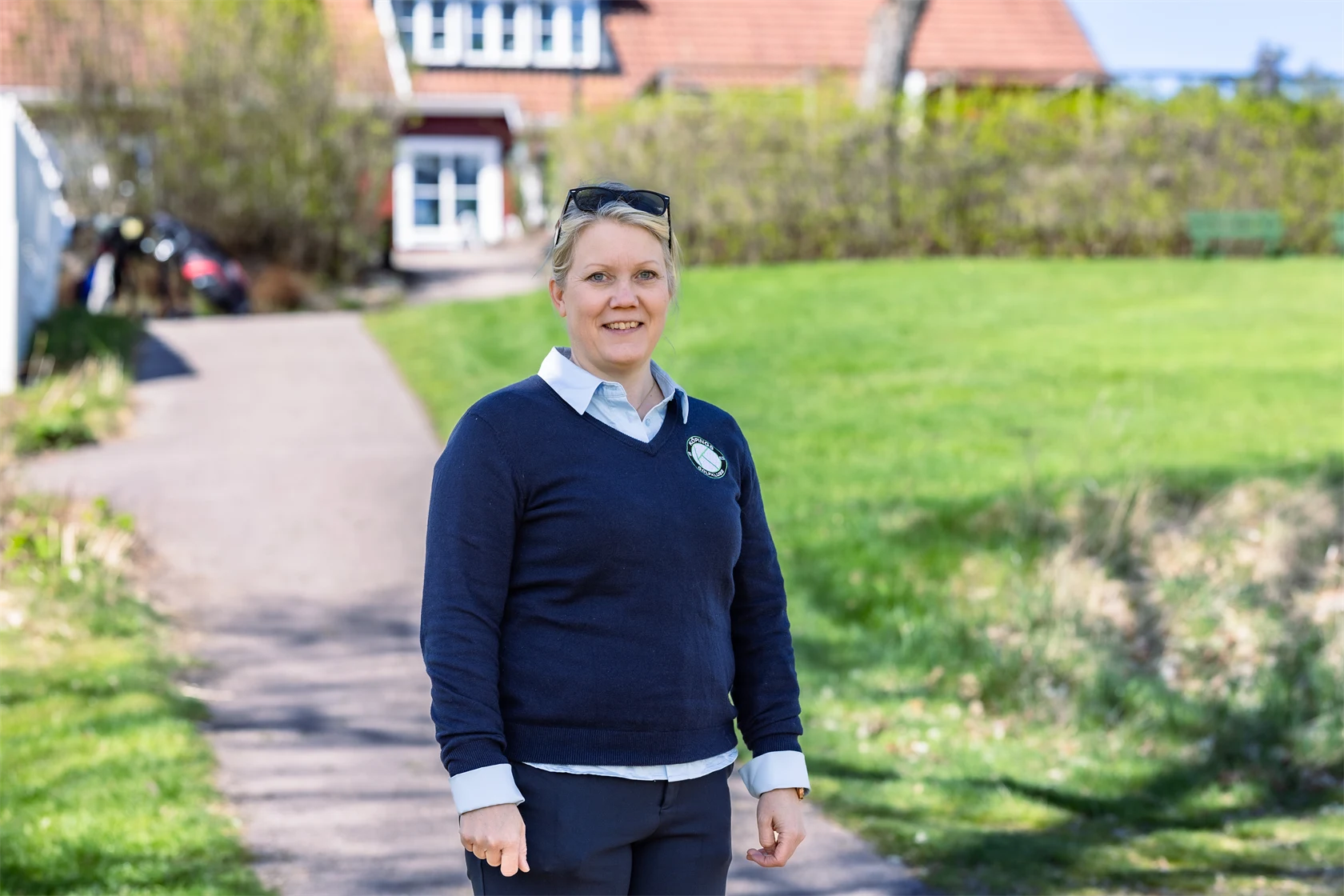 Bild på Lena Björkdahl som är klubbchef för Köpings Golfklubb. Hon står utomhus utanför golfklubben.