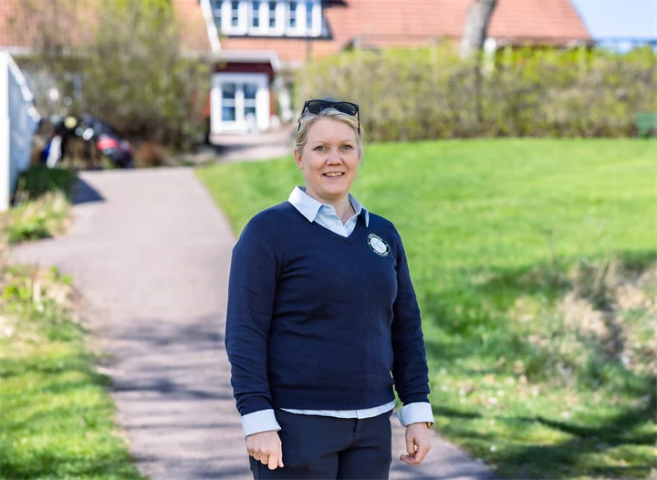 Bild på Lena Björkdahl som är klubbchef för Köpings Golfklubb. Hon står utomhus utanför golfklubben.