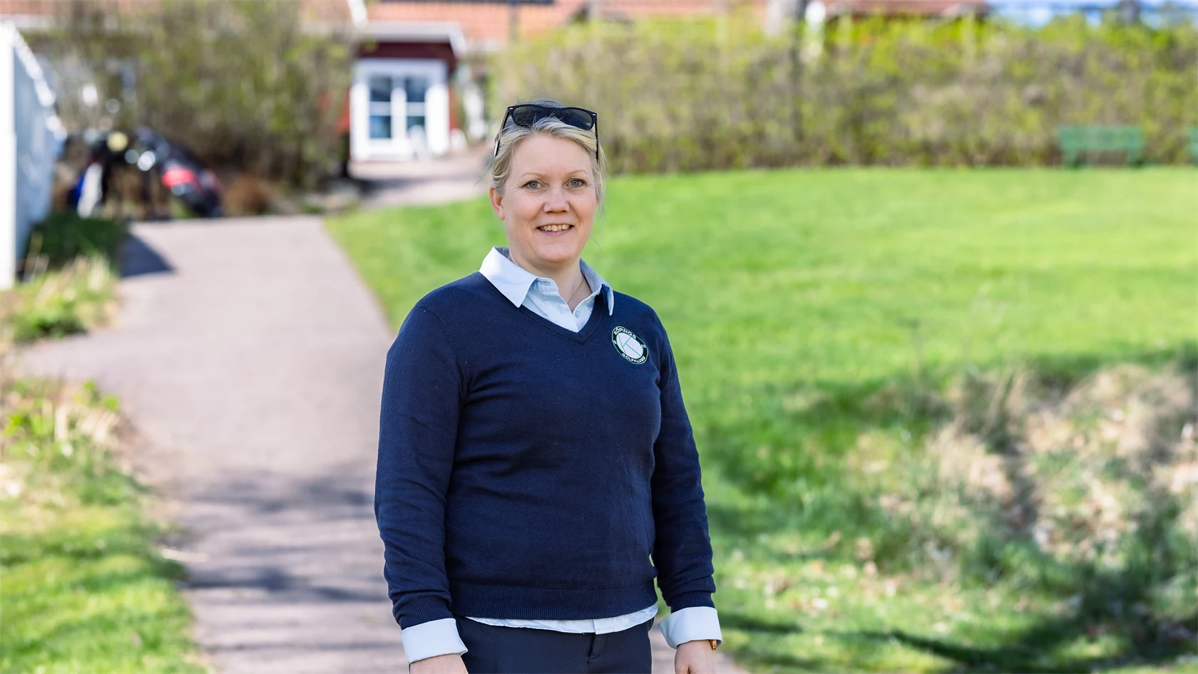 Bild på Lena Björkdahl som är klubbchef för Köpings Golfklubb. Hon står utomhus utanför golfklubben.