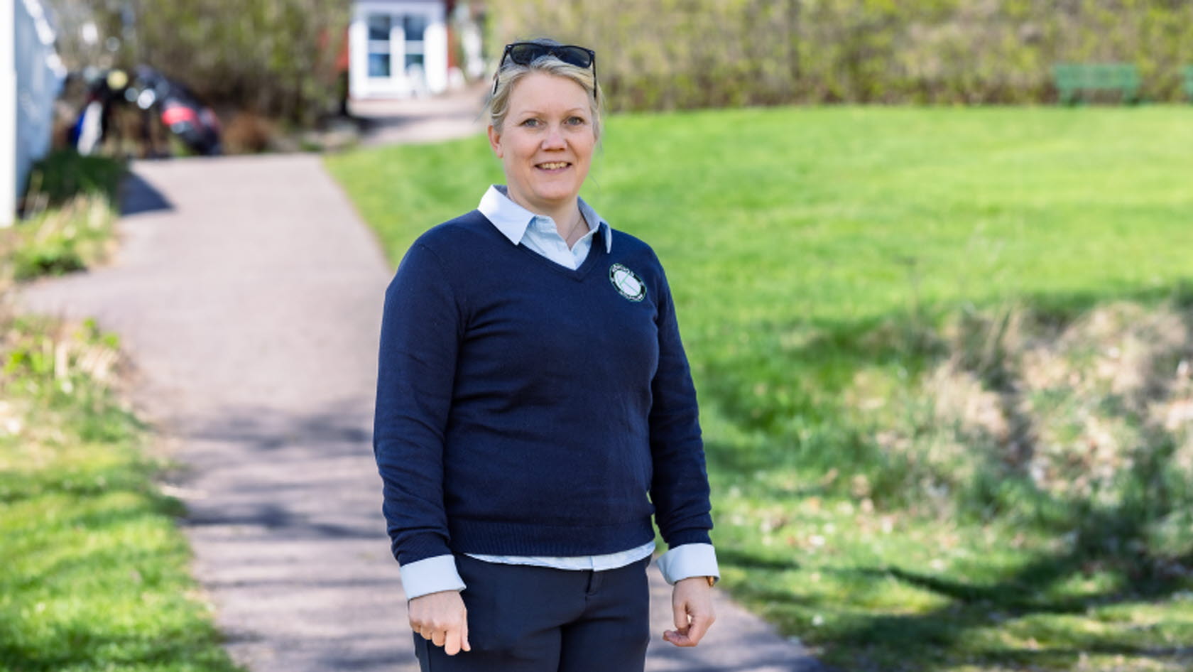 Bild på Lena Björkdahl som är klubbchef för Köpings Golfklubb. Hon står utomhus utanför golfklubben.